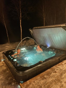 Aurora mökki kylpyaltaalla Lapissa Tenojoen rannassa, Nuorgam, Finlandia
